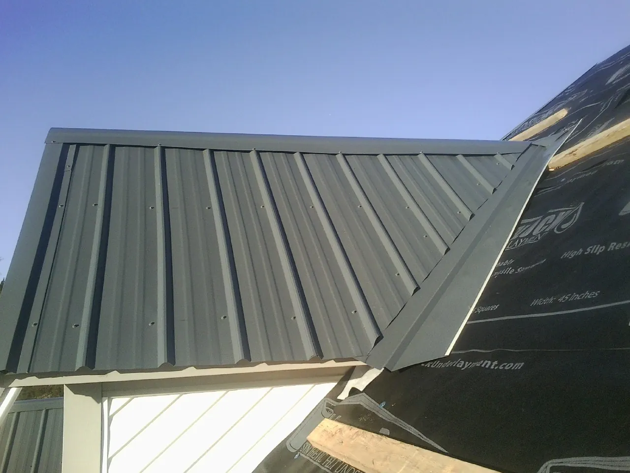 Gray metal roof panels going on over a garage gable in Chardon