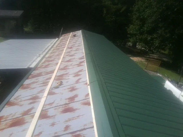 Old rusted panels beside newly installed green metal roofing — Wind Damage Roof Repair by Roofing Brothers in Chardon