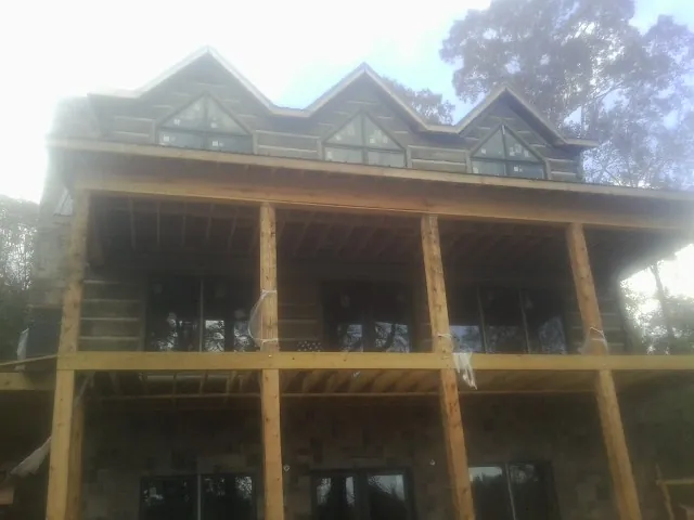 Dormers and porch framing on a large log home under construction — Roof Coating work by our crew in Chardon