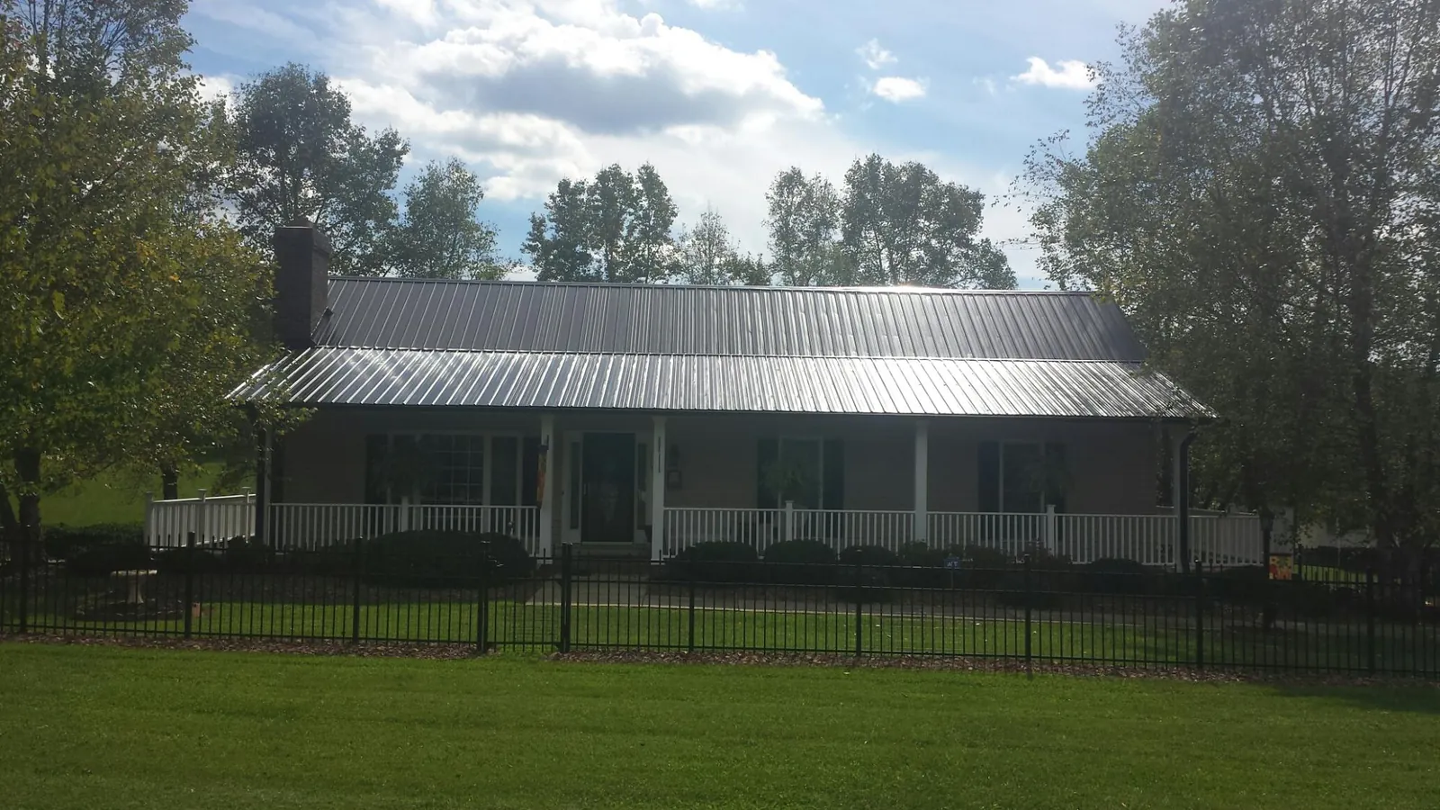 Gray metal roof on a brick ranch with a full width front porch — Gutter Guard Installation work by our crew in Chardon