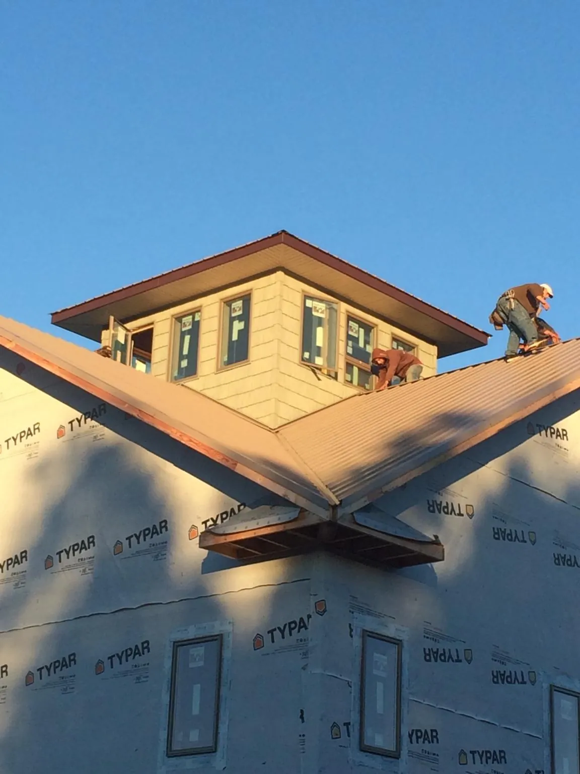 Roofers working around a rooftop cupola on a new metal roof at sunset — Roof Waterproofing in Chardon by Roofing Brothers